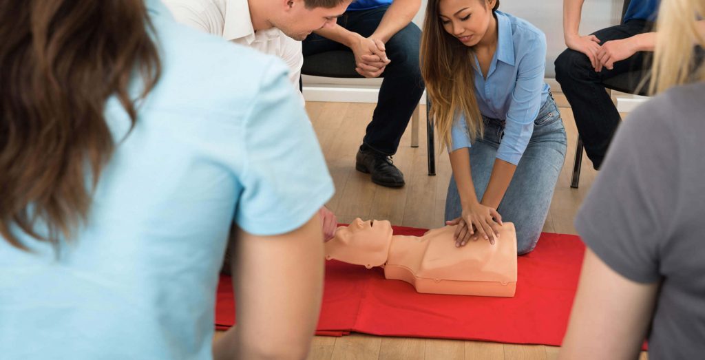 A woman performing CPR on a dummy patient during the class